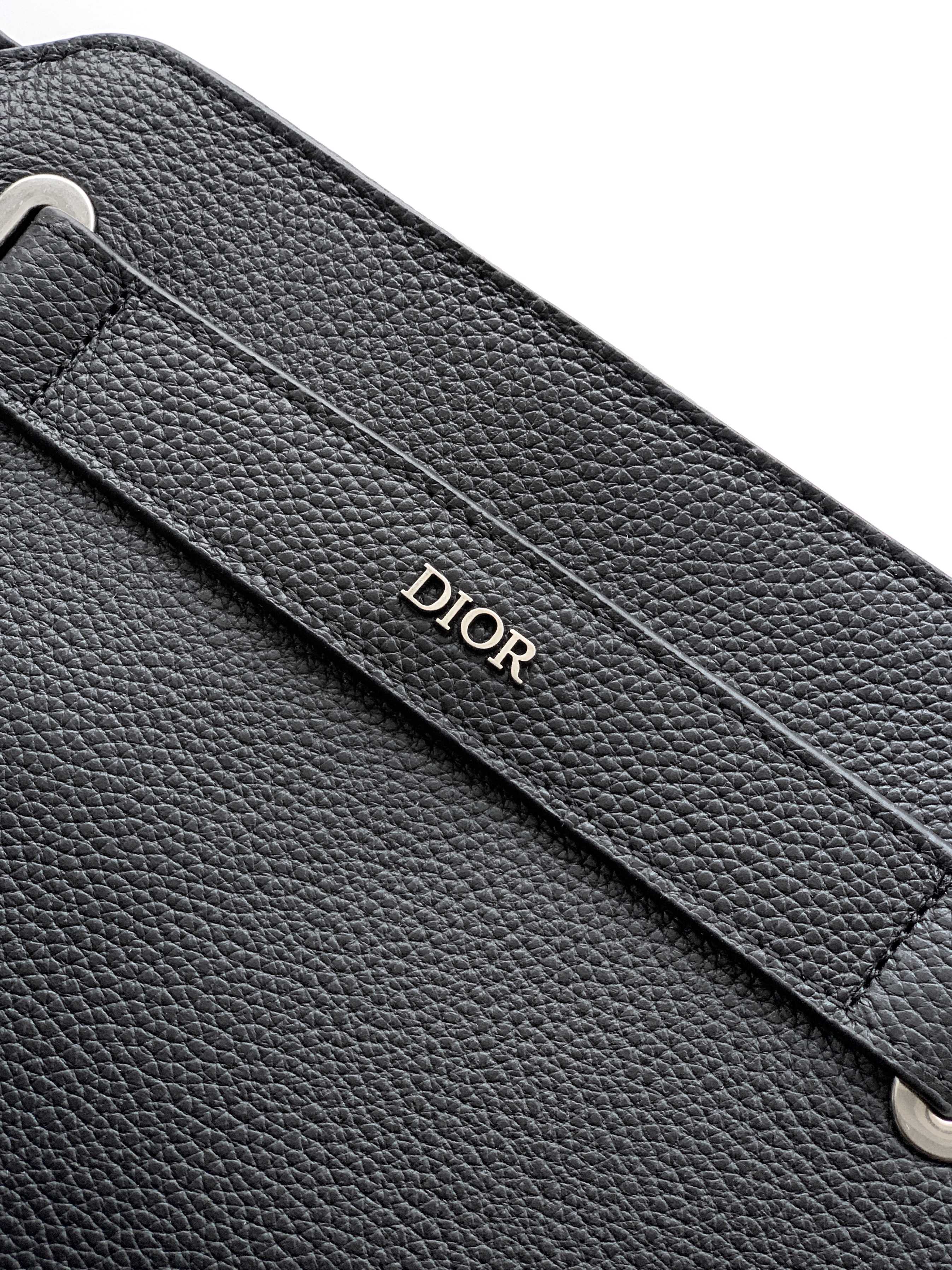 Black Dior leather strap panel with debossed Dior logo and visible stitching.