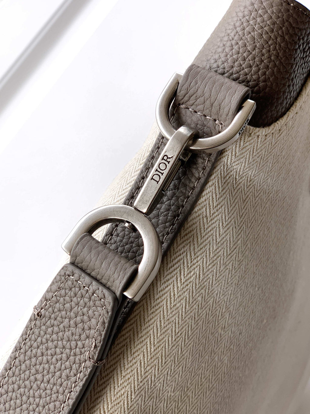 Dior bag close-up of logo-stamped strap and silver D-ring hardware