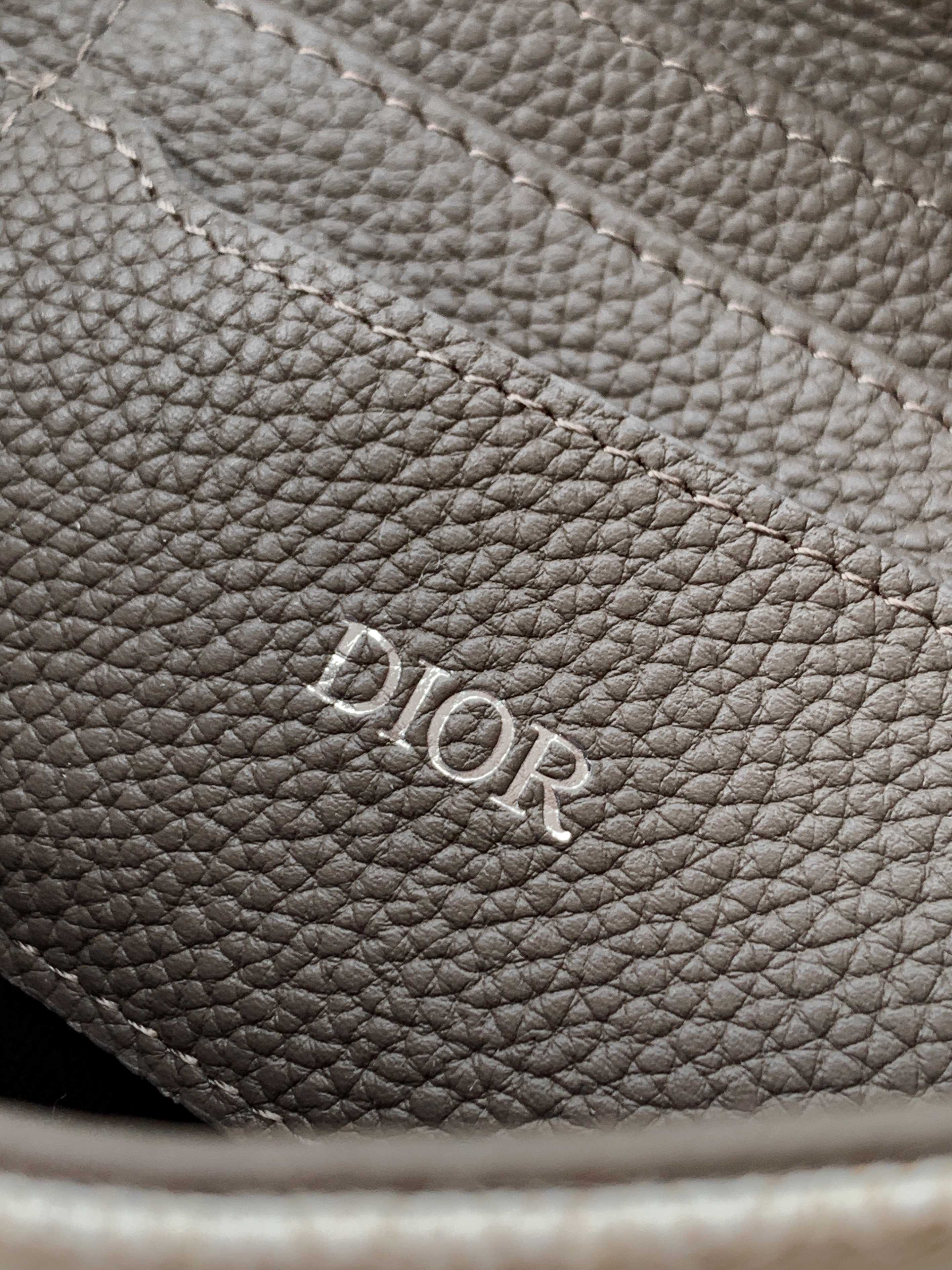 Dior bag pebbled leather close-up with engraved Dior logo