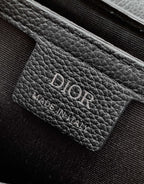 Dark leather bag label with DIOR embossed, textured grain and stitched edge