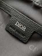 Dior logo leather patch on a black textured bag, showing detailed grain