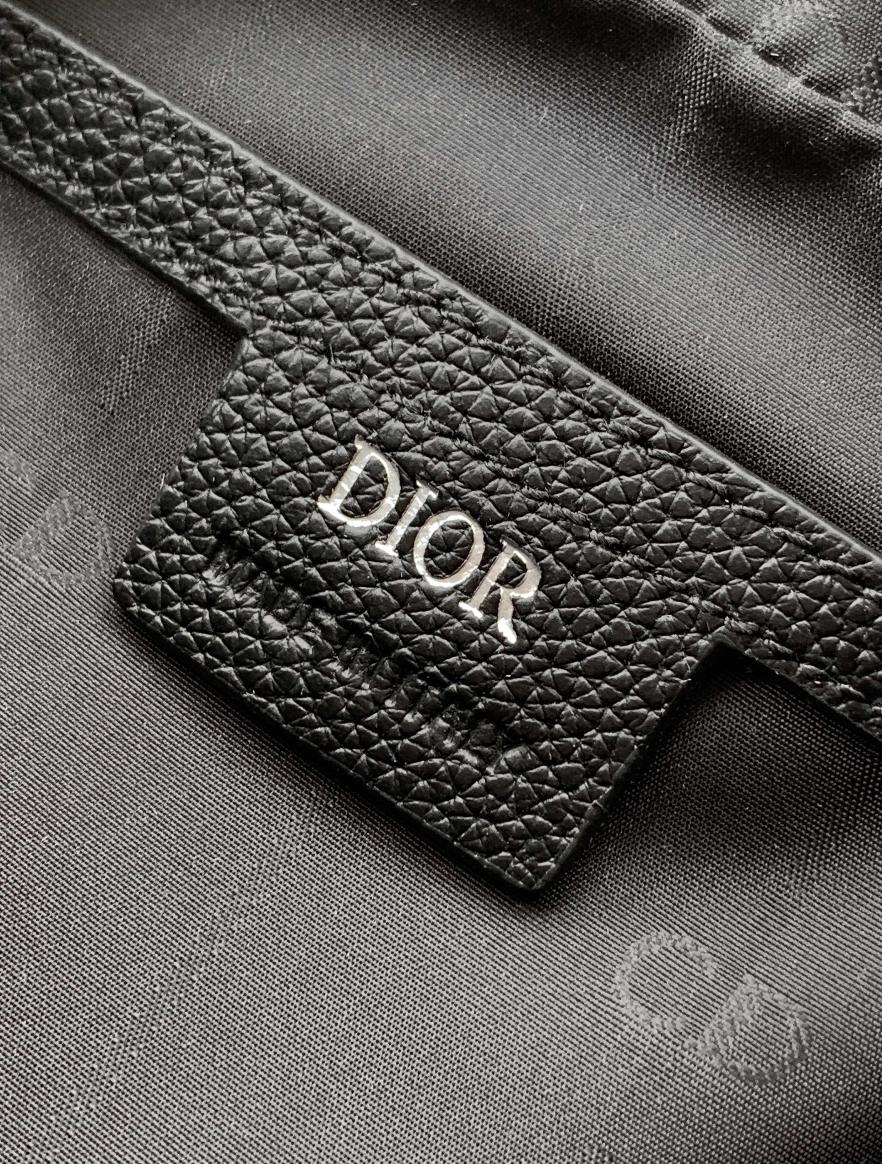 Dior logo leather patch on a black textured bag, showing detailed grain