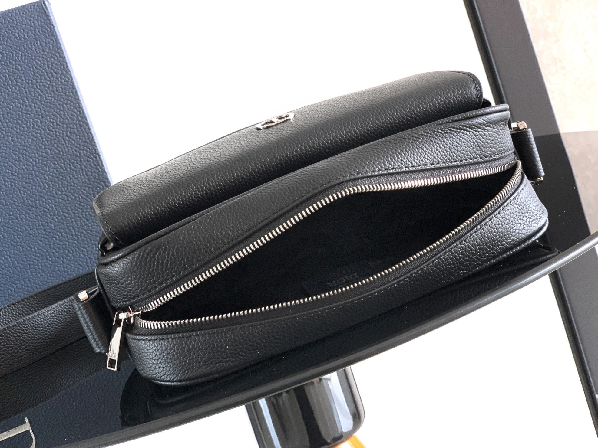 Men's Dior crossbody bag showing dual zippers and black leather texture