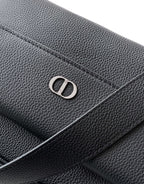 Dior logo emblem on black textured leather bag flap and stitching