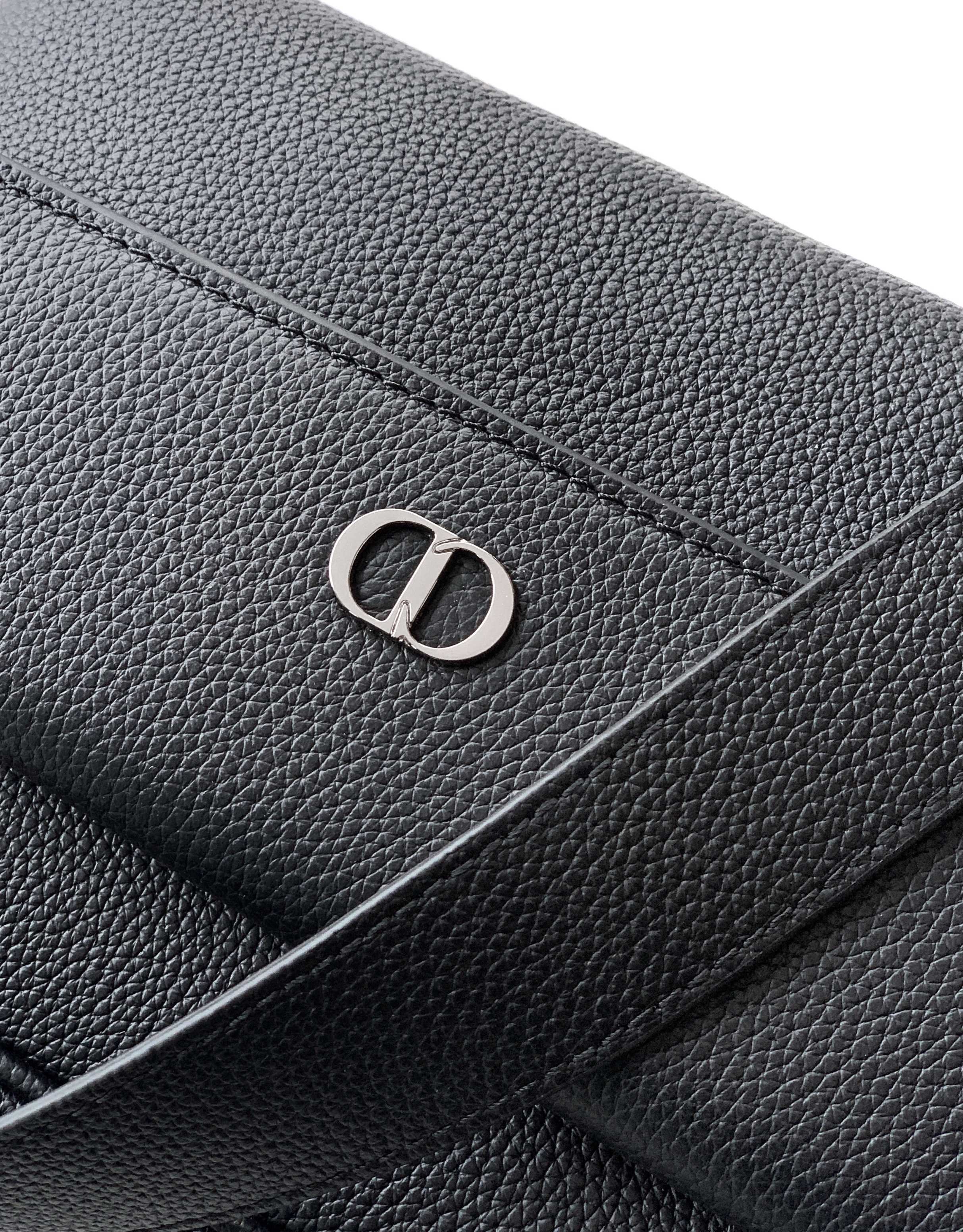 Dior logo emblem on black textured leather bag flap and stitching
