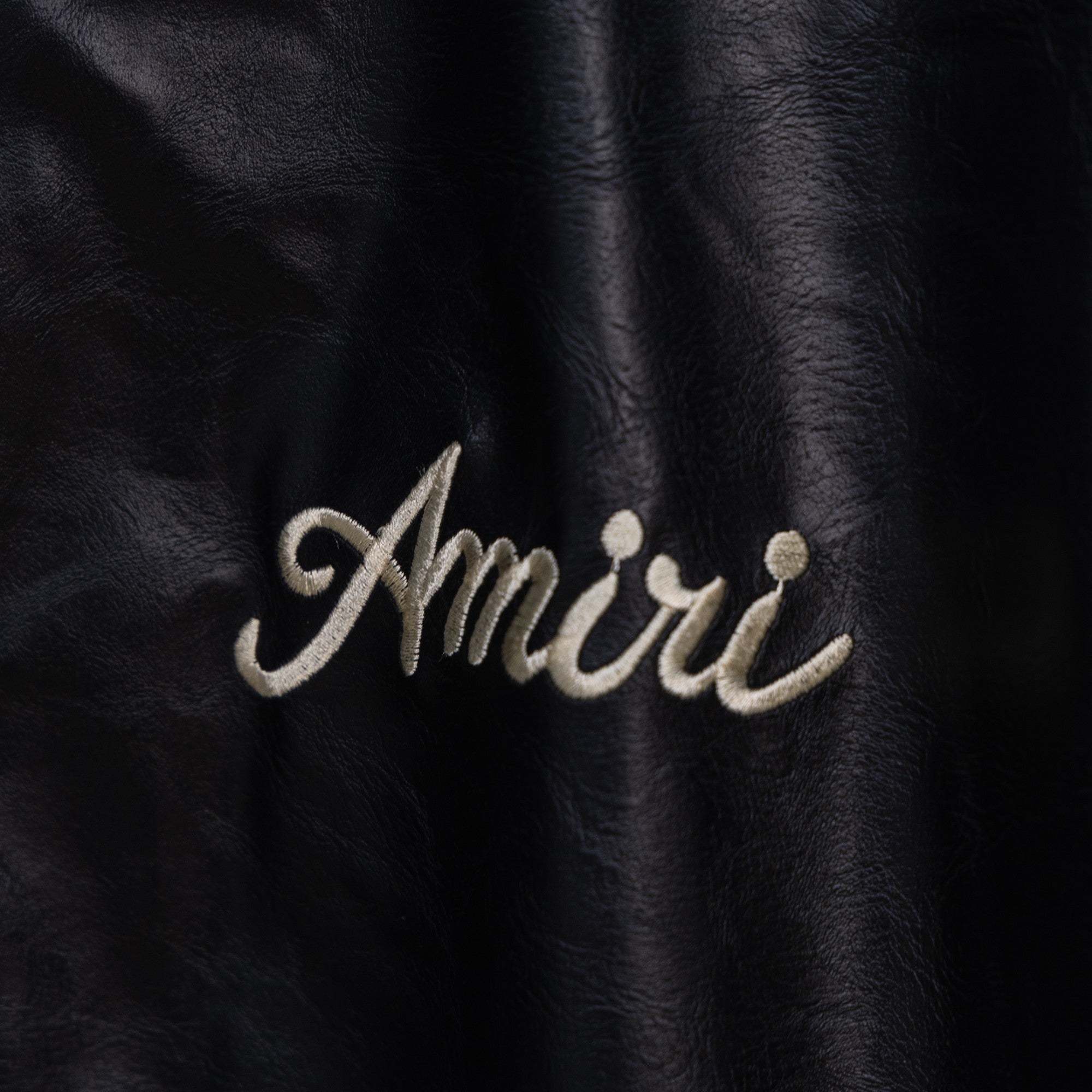 Amiri black leather jacket front with embroidered “Amiri” script logo