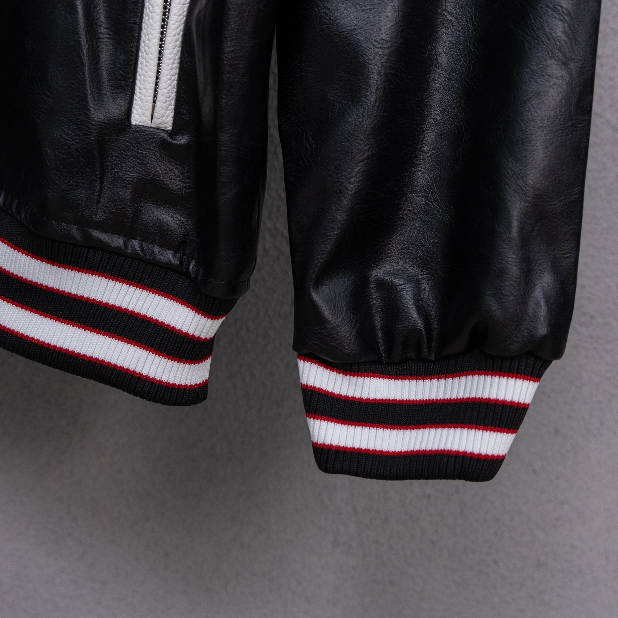 Amiri black leather bomber jacket cuffs with red, white, and black striped rib trim
