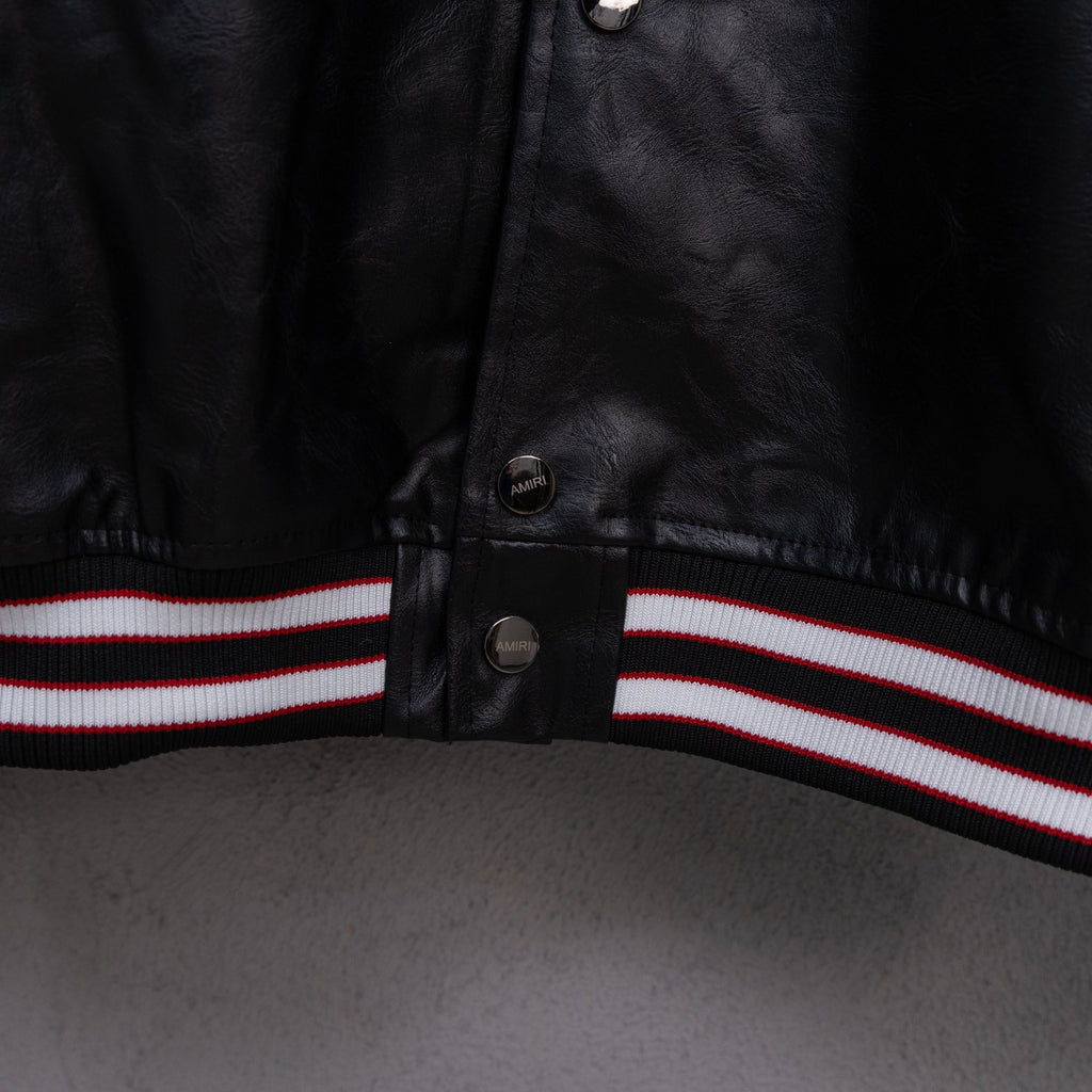 Amiri black leather jacket front hem with red, white, and black striped ribbed trim
