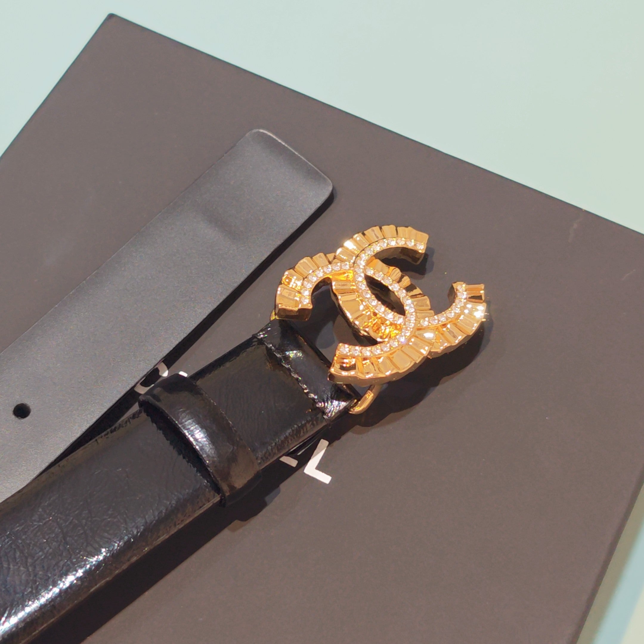 Chanel belt close-up of gold-tone CC buckle with rhinestones on dark leather