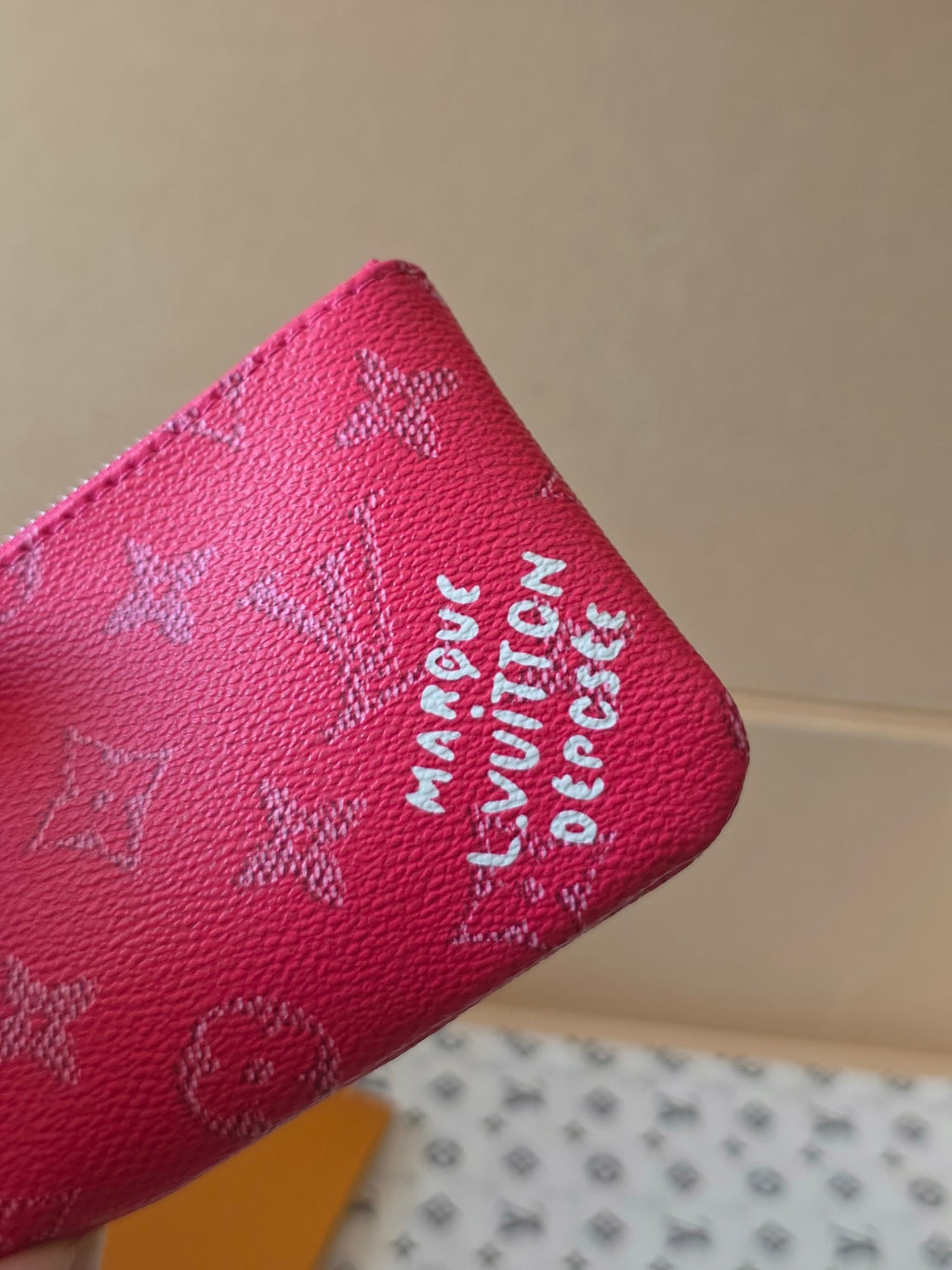 Louis Vuitton pink monogram bag close-up with embossed logo text on the side