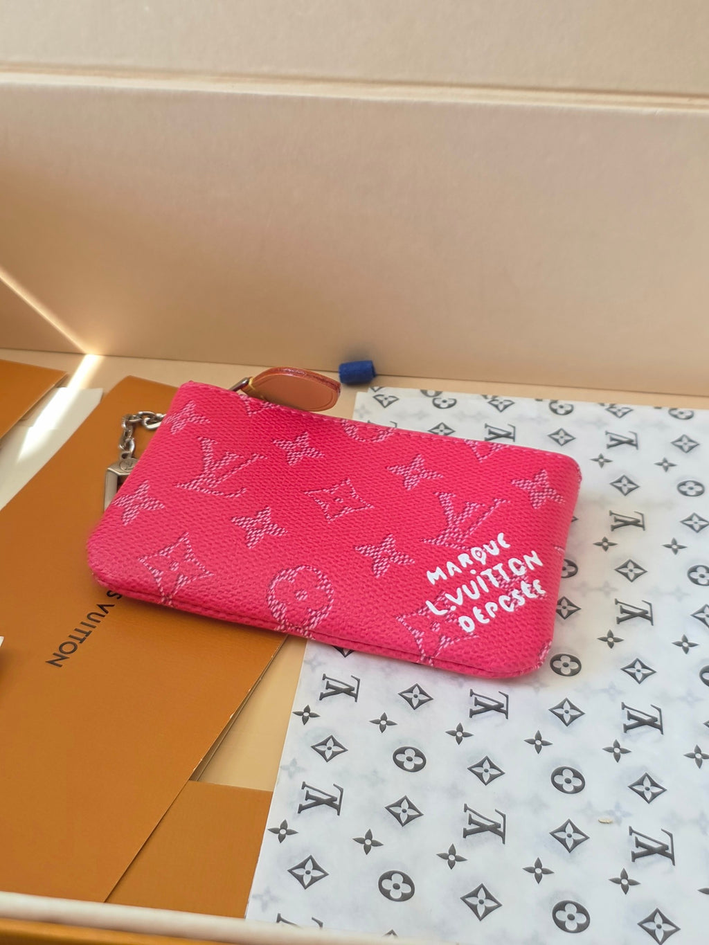 Hot pink Louis Vuitton small bag with zip top and monogram pattern, flat lay
