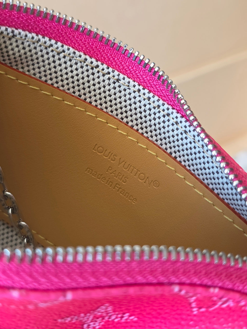 Louis Vuitton logo and text on brown interior lining of small pink zip bag