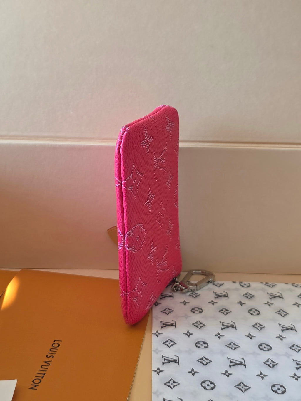 Hot pink Louis Vuitton small bag side view with monogram texture and zipper edge