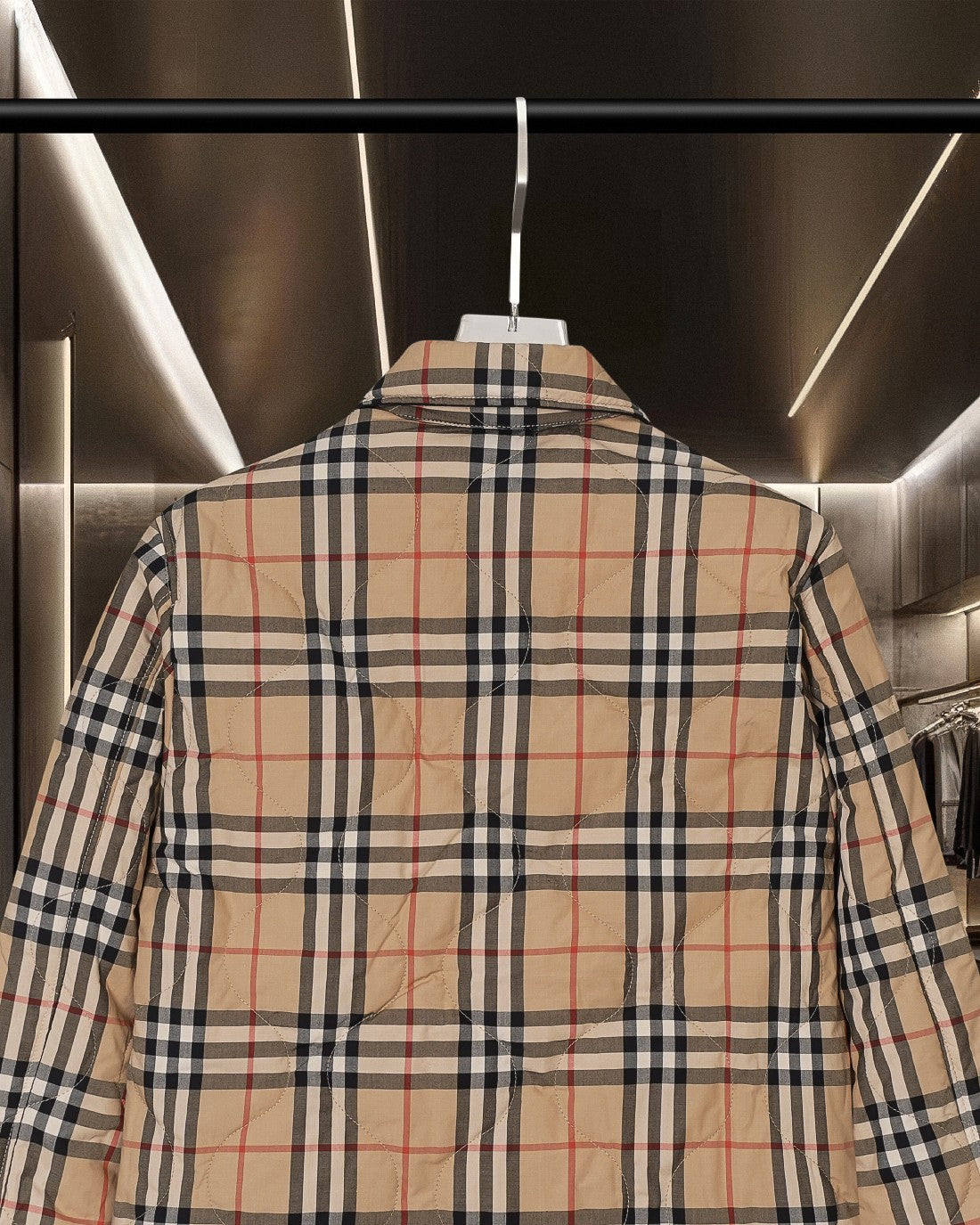 Long plaid quilted jacket back view with stitched yoke and full-length paneling.