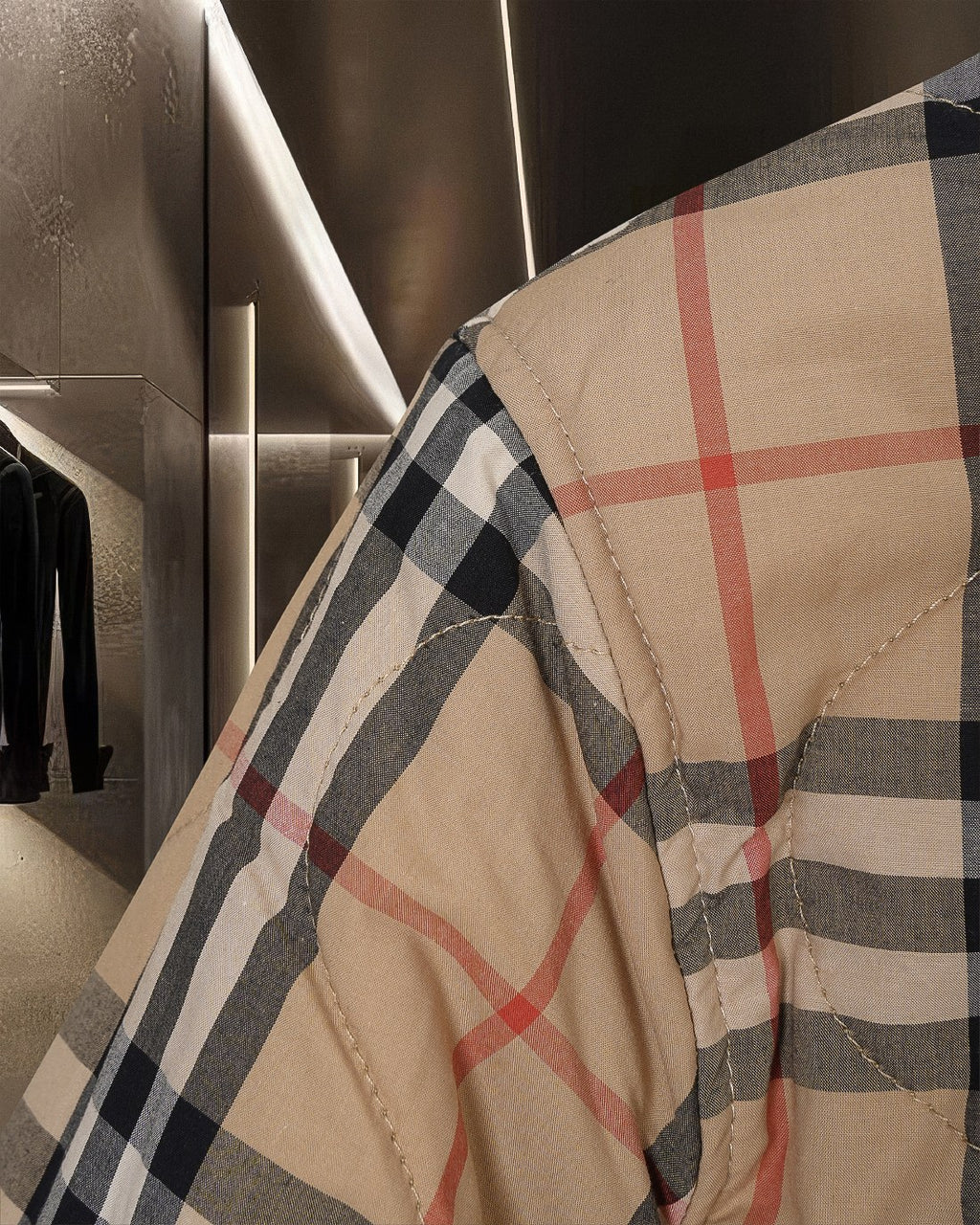 Plaid quilted jacket shoulder and upper sleeve area in beige, black, and muted red lines.