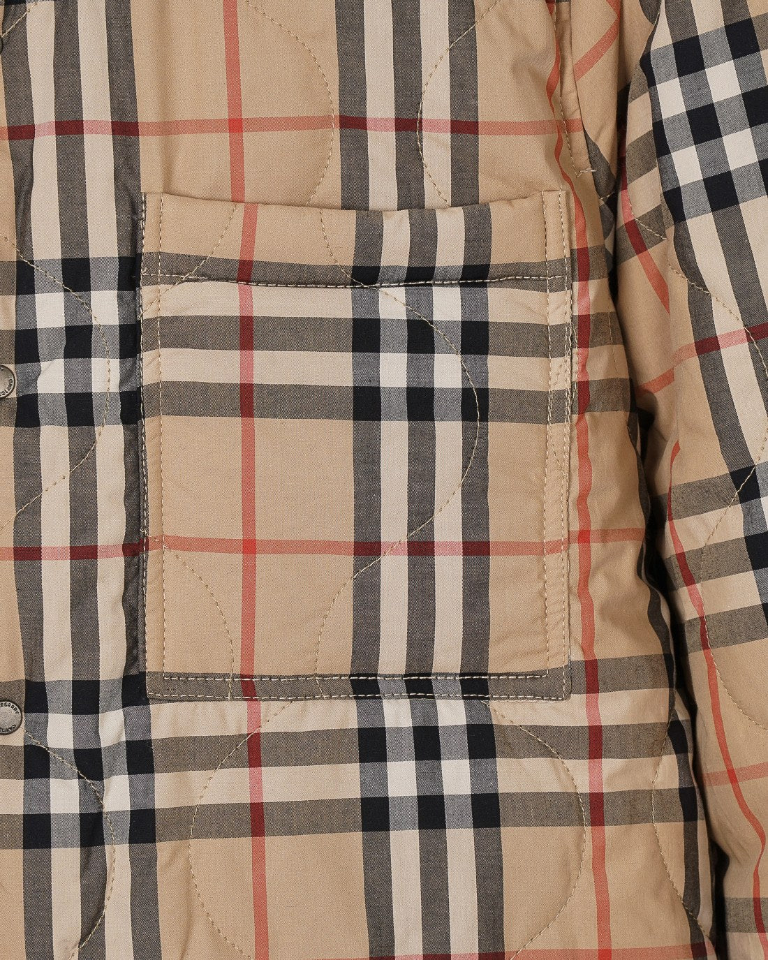 Plaid quilted jacket pocket panel with stitching in beige, black, white, and red stripes.