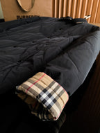 Burberry long quilted coat with dark outer layer and plaid-lined cuff at sleeve end.