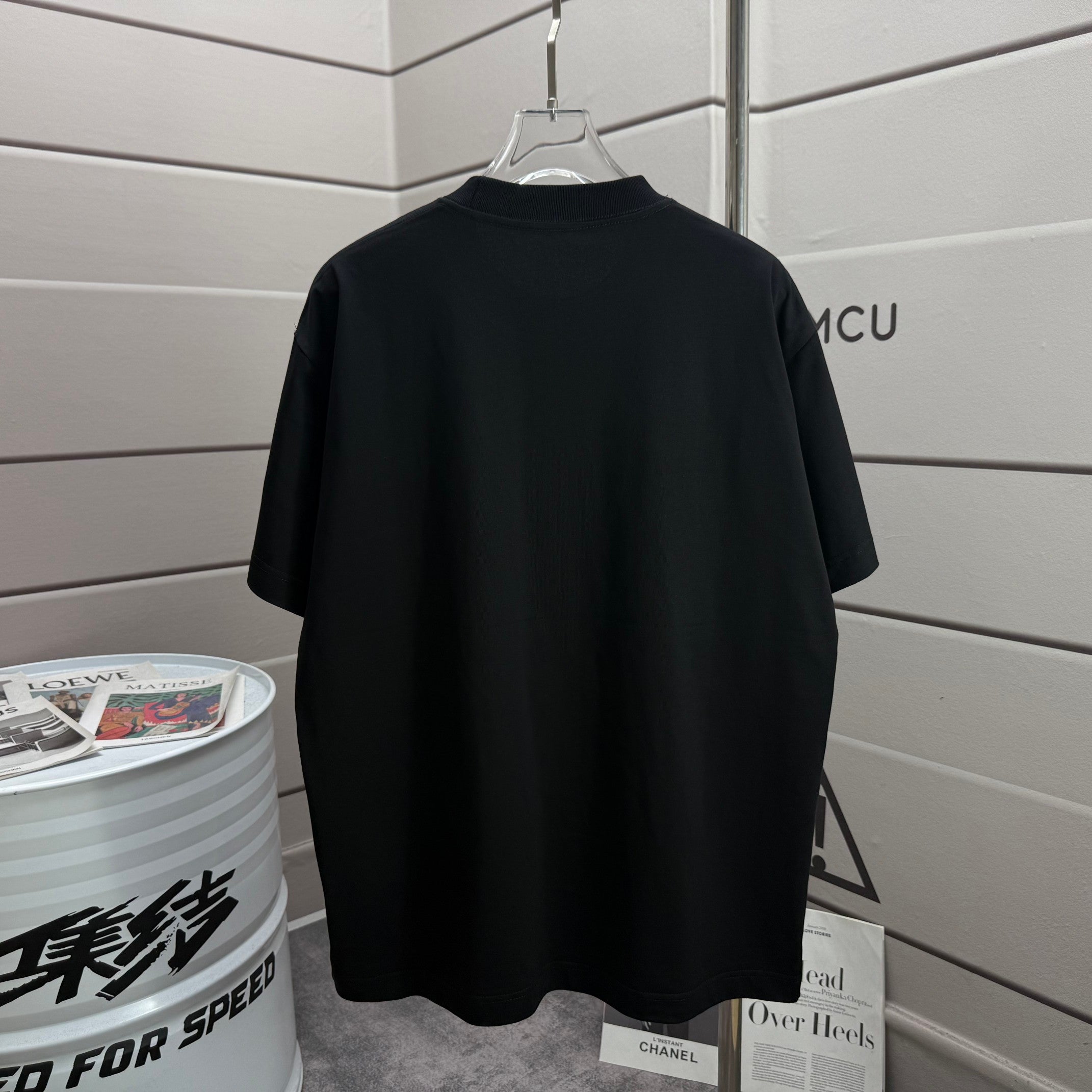 Black crew-neck T-shirt with short sleeves, plain back view on hanger