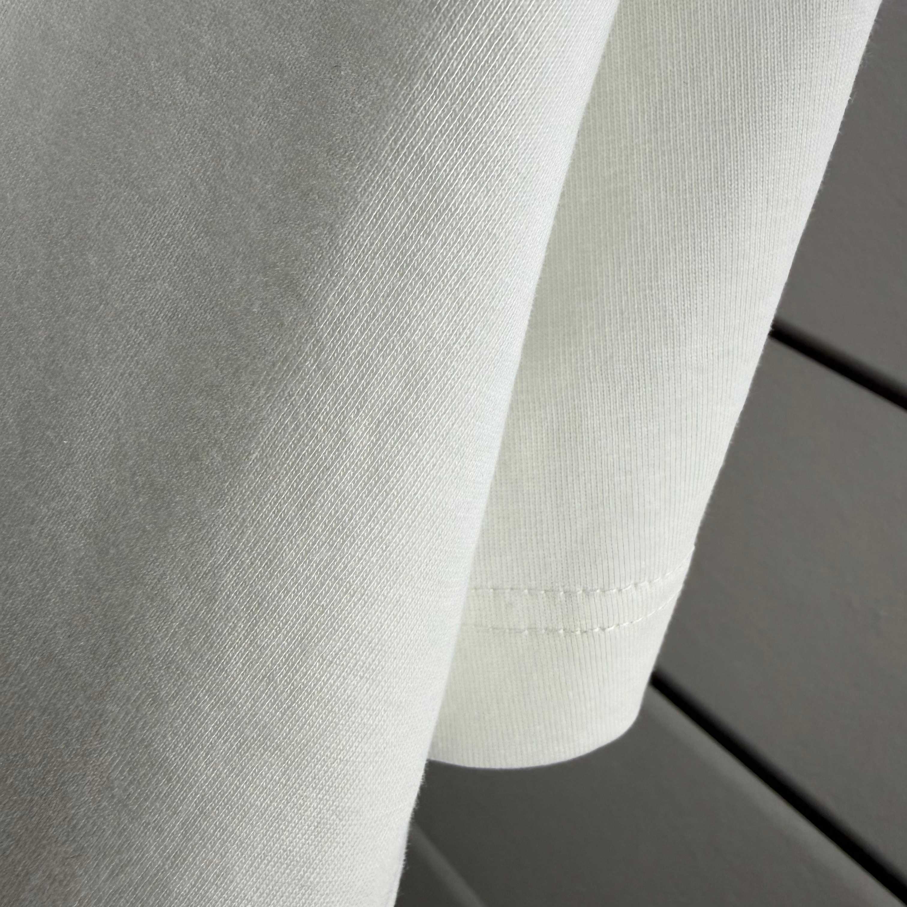 White T-shirt fabric texture and stitched sleeve cuff detail.