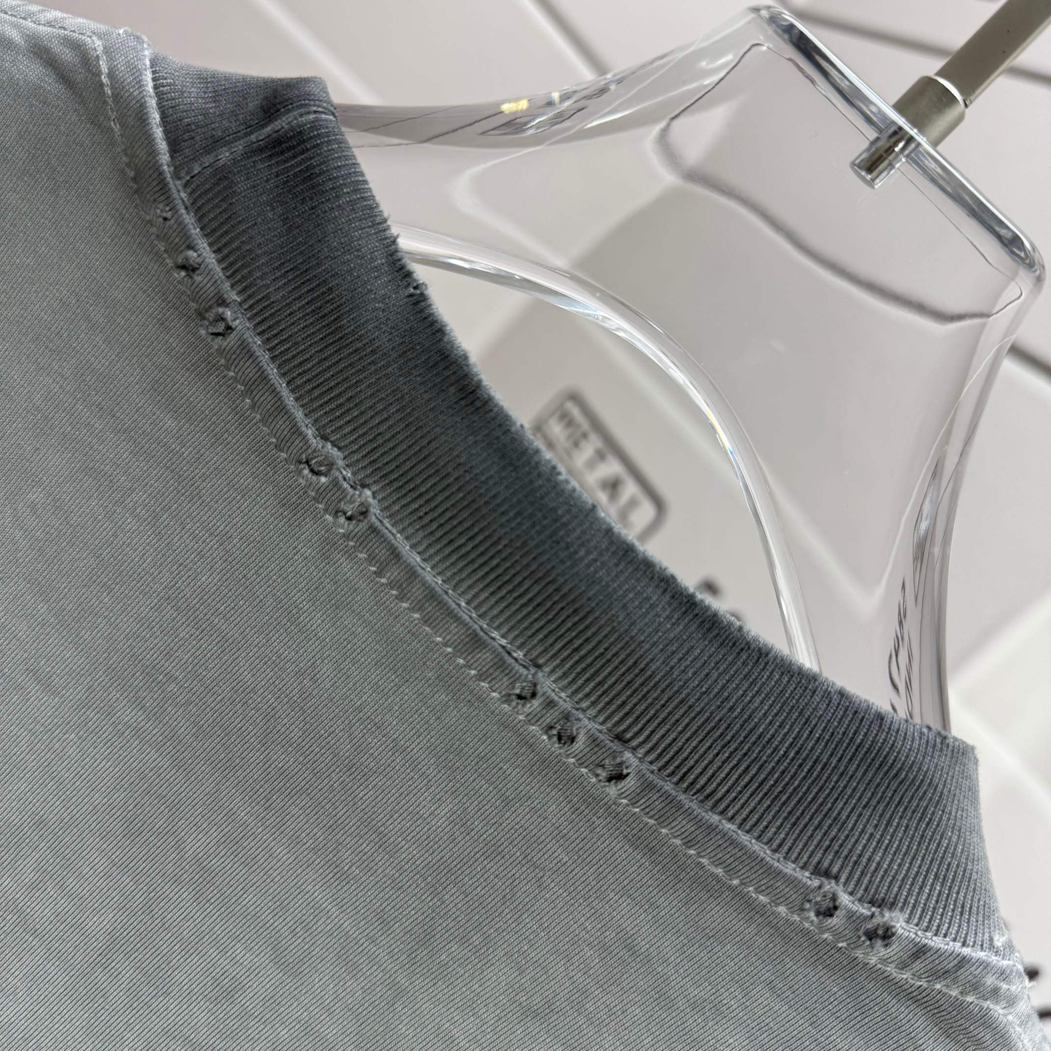 Sage gray T-shirt collar seam with inner brand label.