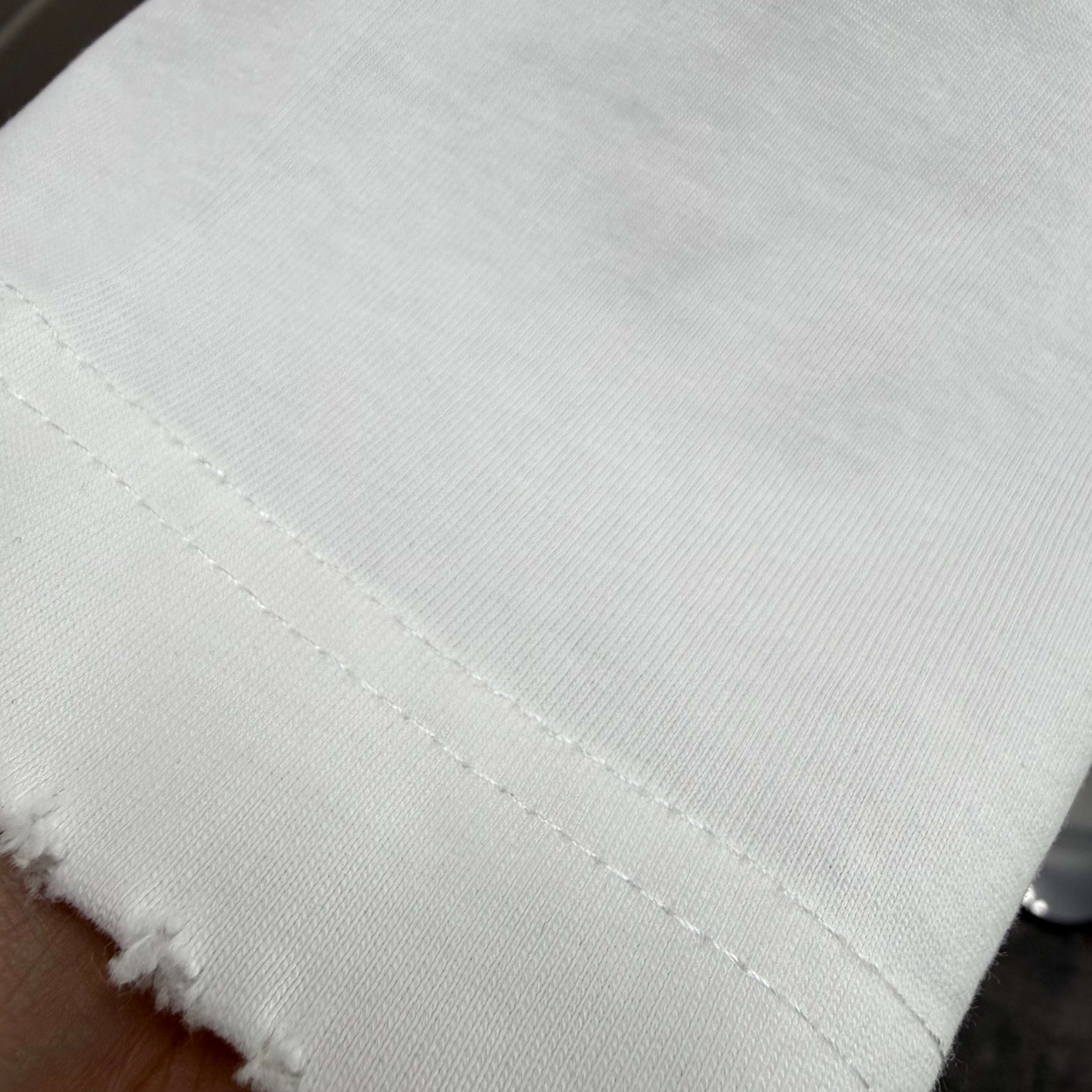 White T-shirt hem stitching detail with distressed frayed edge