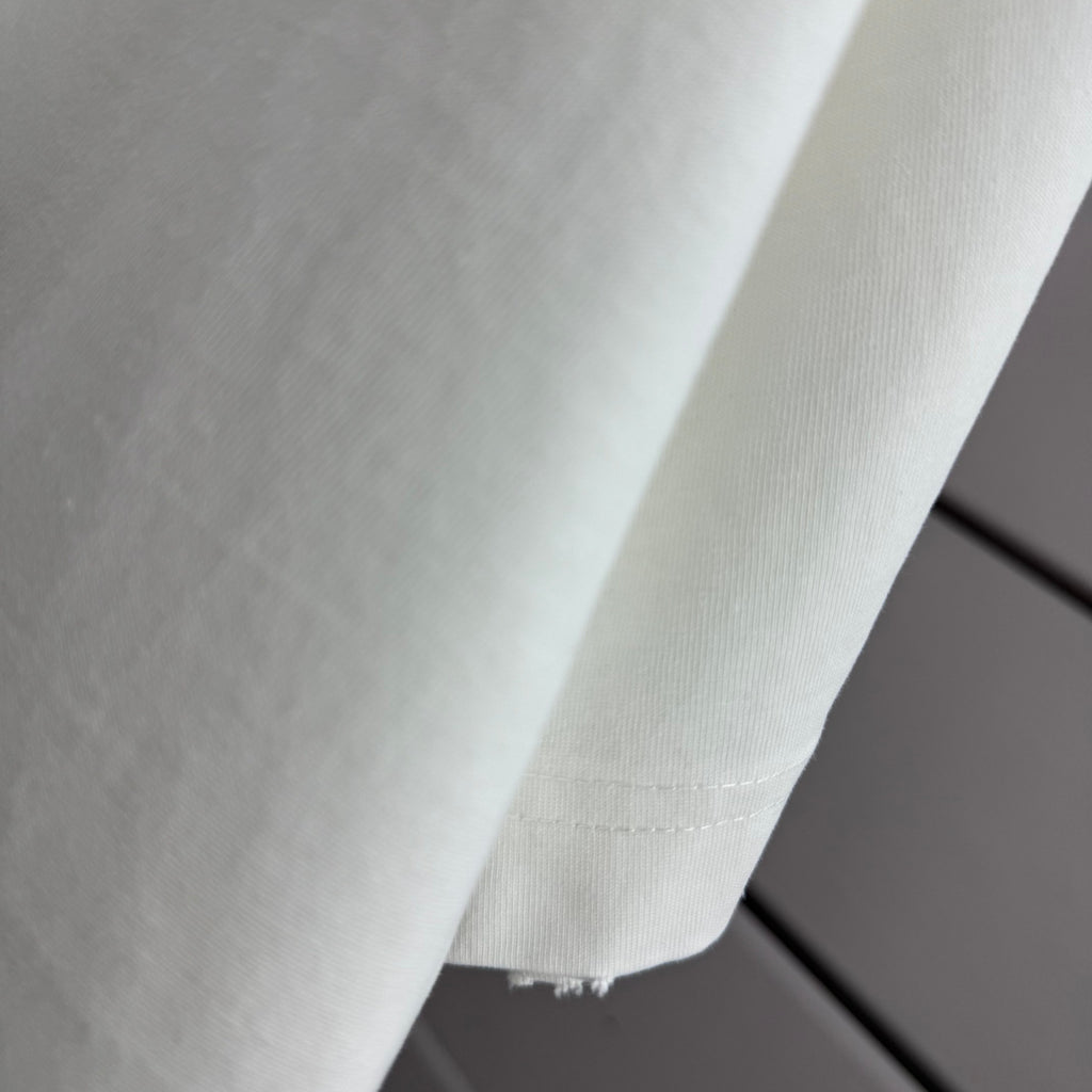 Off-white T-shirt fabric close-up with stitched side seam
