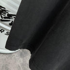 Black T-shirt hem close-up with curved stitched edge