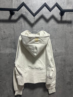 Cream zip-up hoodie with hood, front pocket, and small gold logo detail