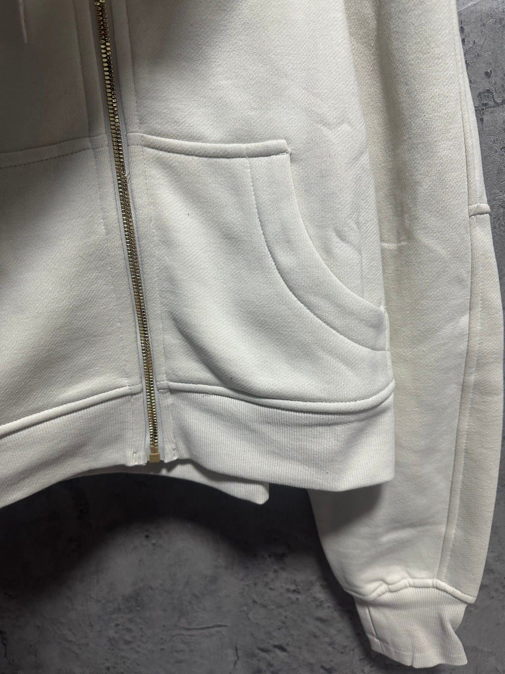 Cream hoodie front pocket and zipper with ribbed cuffs at hem