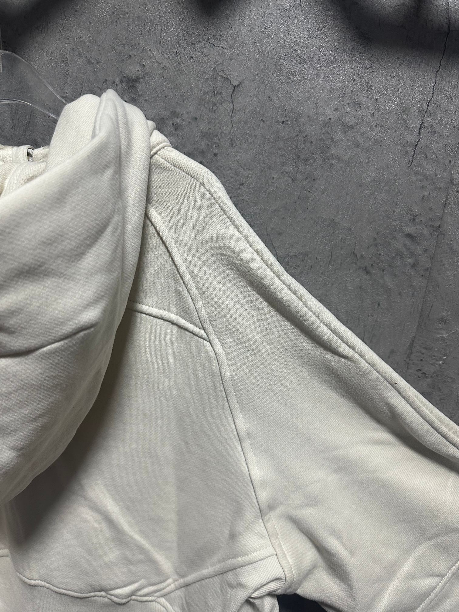 Cream hoodie sleeve and side seam with drawstring channel detail