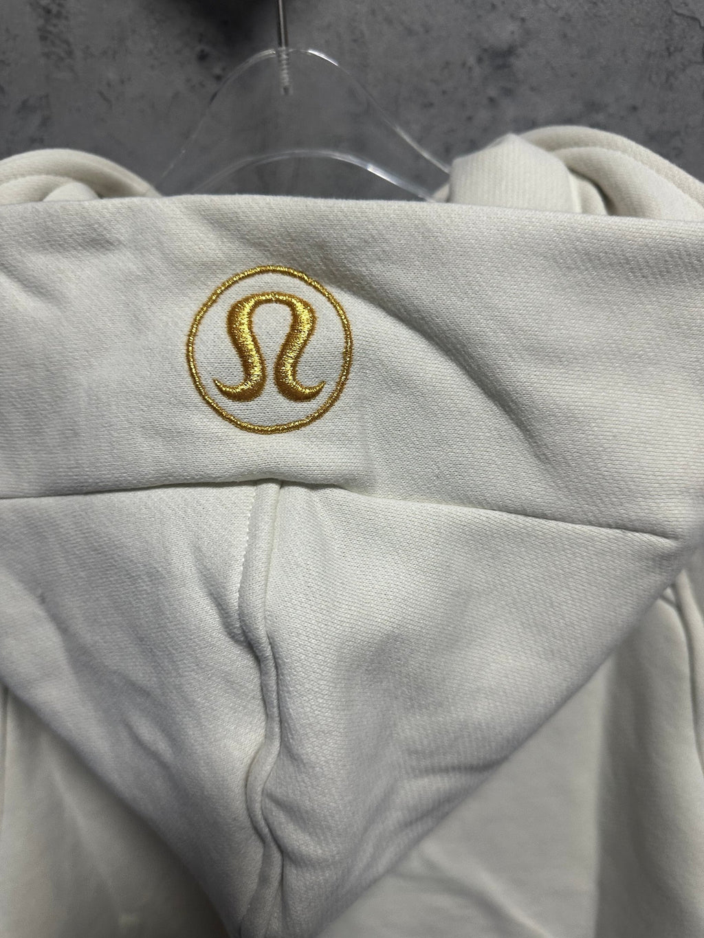 Ralph Lauren zip hoodie, light cream, close-up of embroidered gold monogram on hood