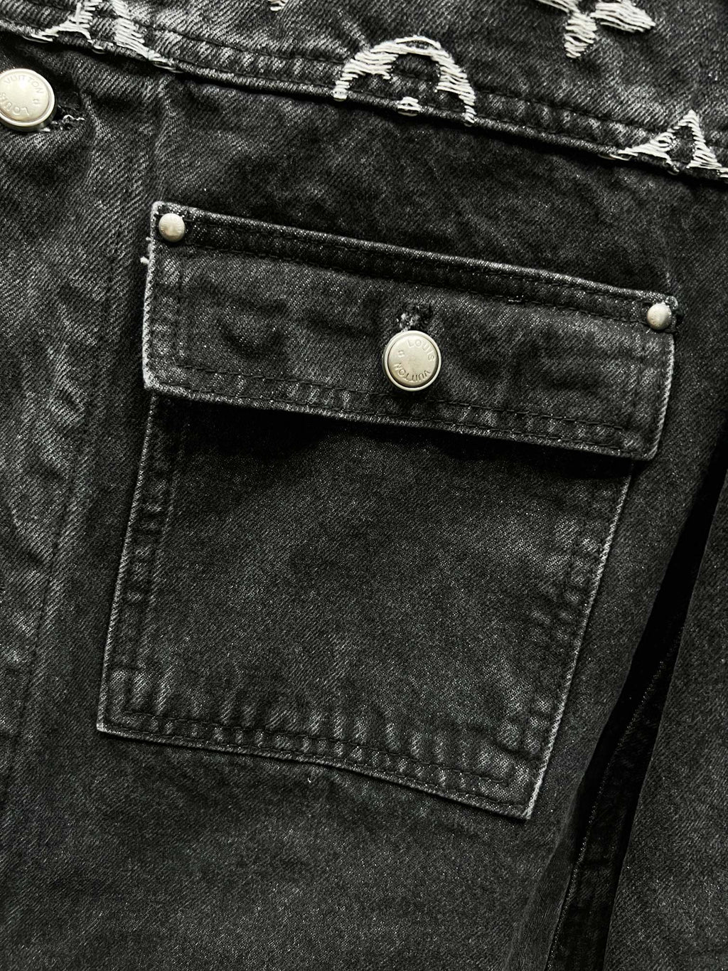 Black denim jacket chest flap pocket with gold-tone button and stitched panel detail