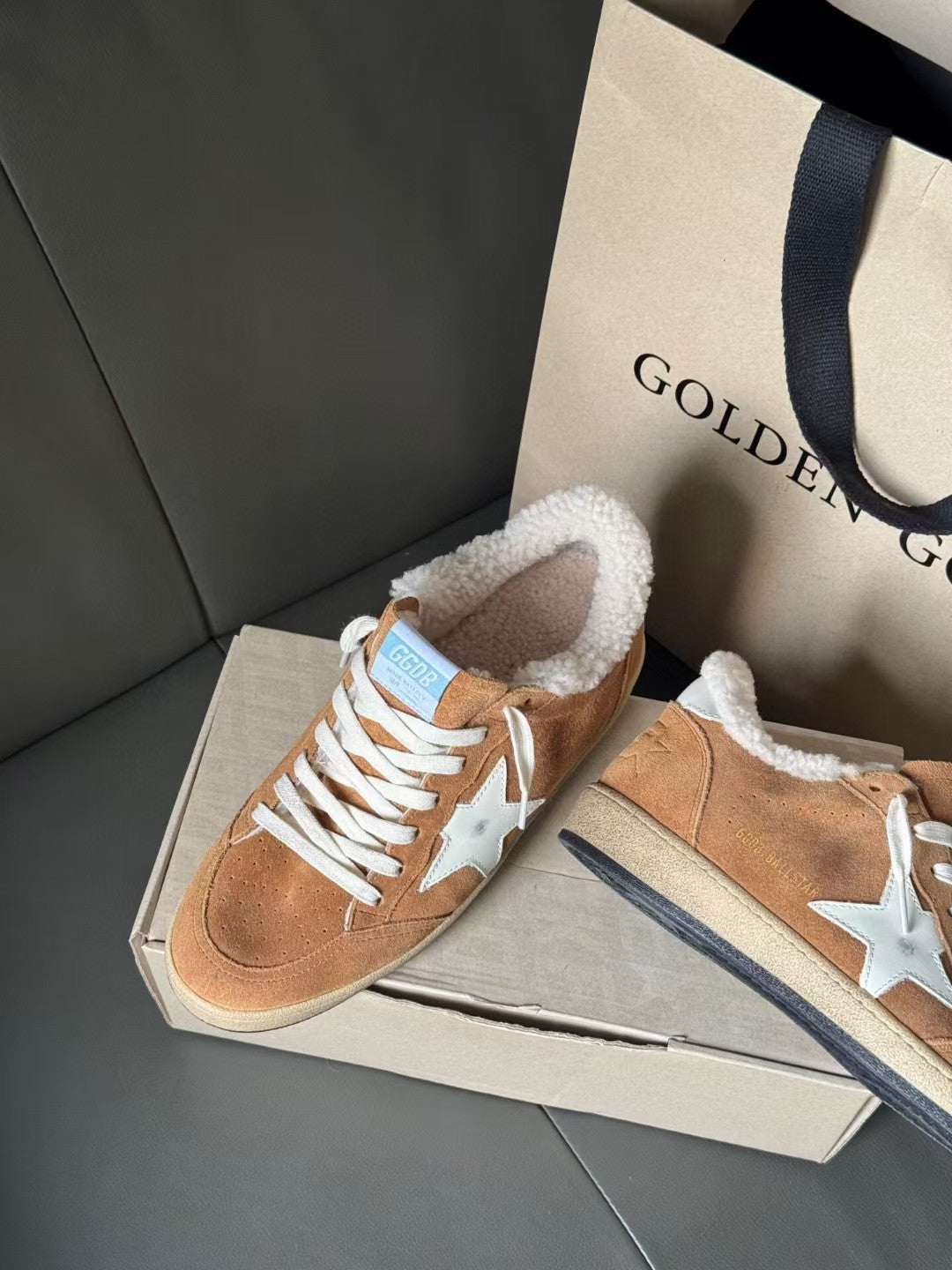 Tan suede sneakers with white star on side, white laces, and fuzzy shearling collar