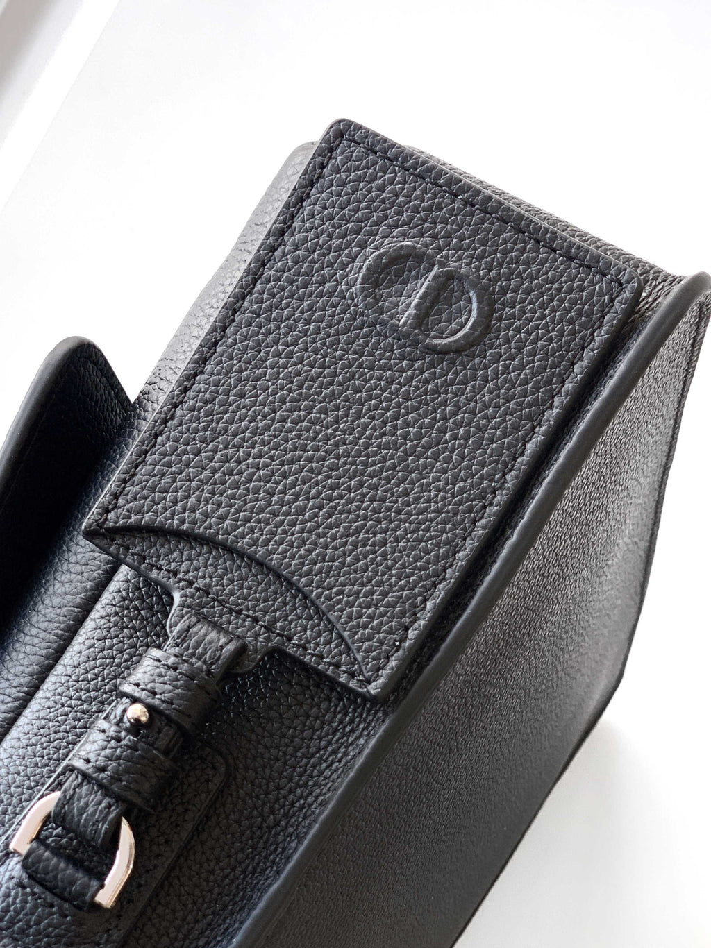 Dior leather crossbody bag close-up with CD logo and strap attachment detail