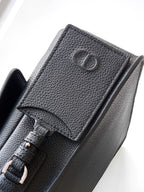 Dior leather crossbody bag close-up with CD logo and strap attachment detail