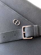 Dior leather bag close-up with CD emblem and metal buckle on textured surface