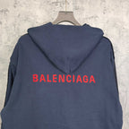 Navy hooded jacket with red BALENCIAGA logo across the back and snap front.