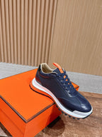 Hermes unisex navy lace-up sneakers with orange trim, white midsole, side view