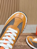 Hermes sneaker close-up, orange leather toe with gray side panel and white laces