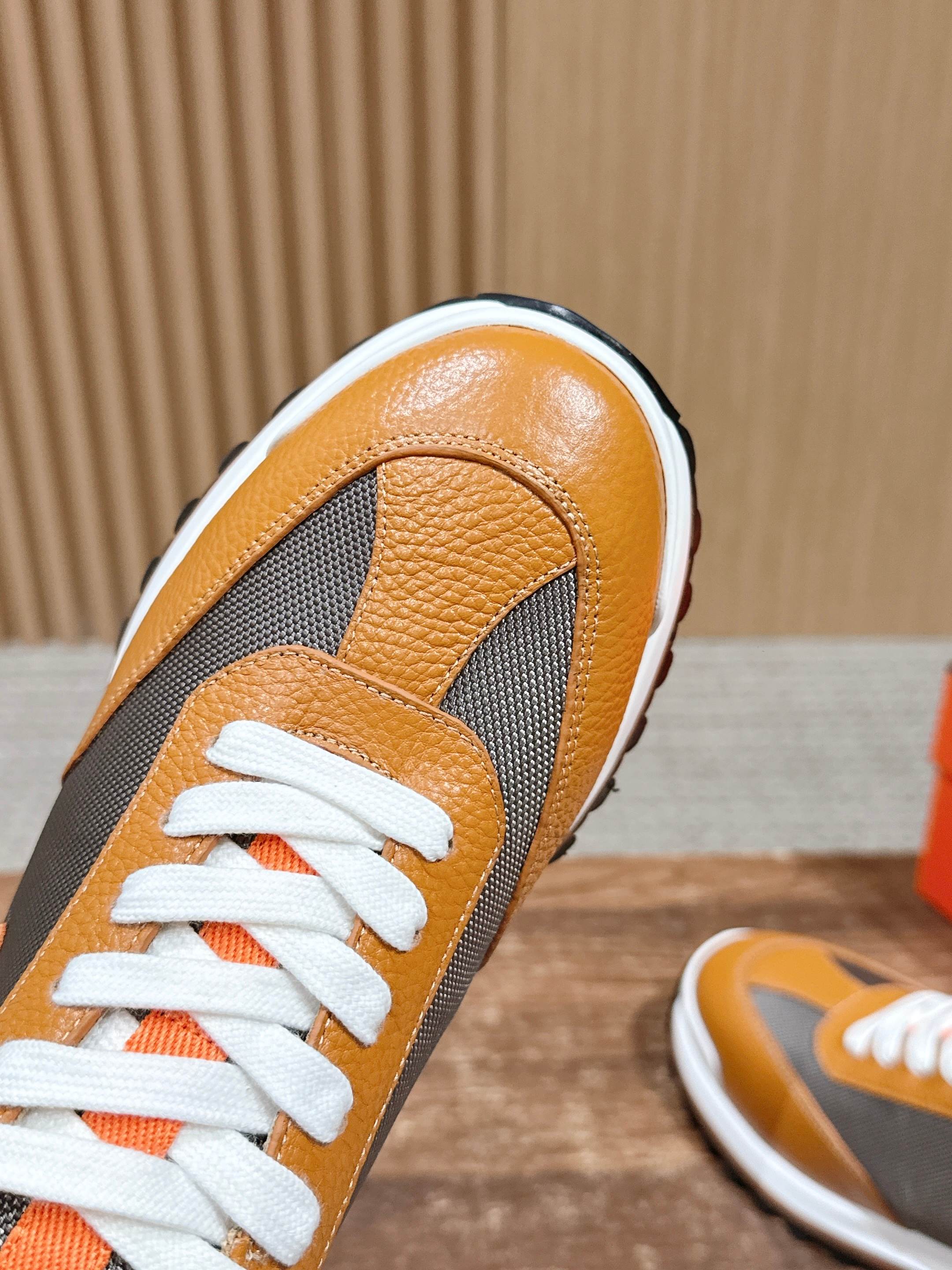 Hermes sneaker close-up, orange leather toe with gray side panel and white laces