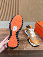 Hermes sneaker outsole view, orange patterned sole with white midsole and laces
