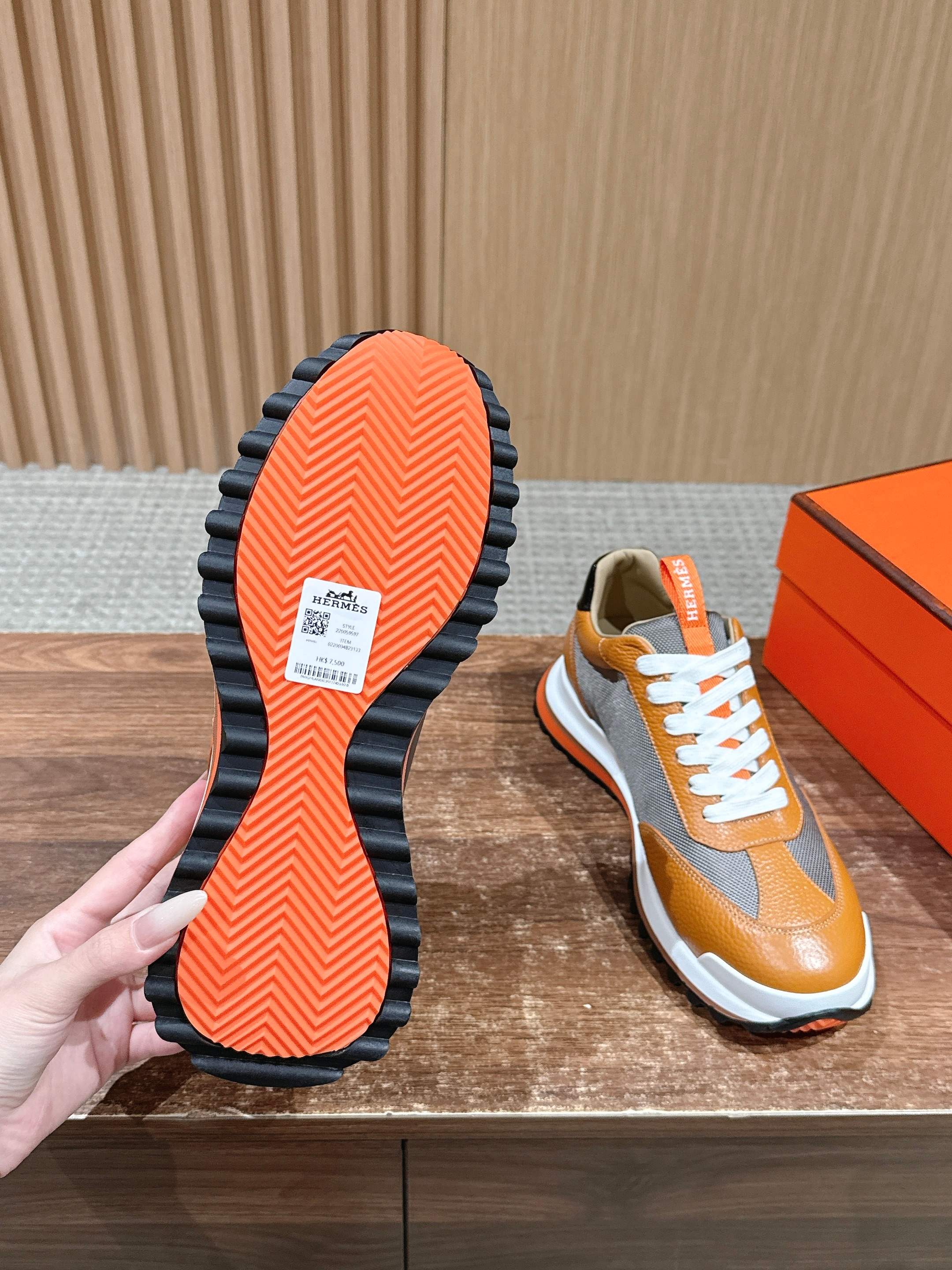 Hermes sneaker outsole view, orange patterned sole with white midsole and laces