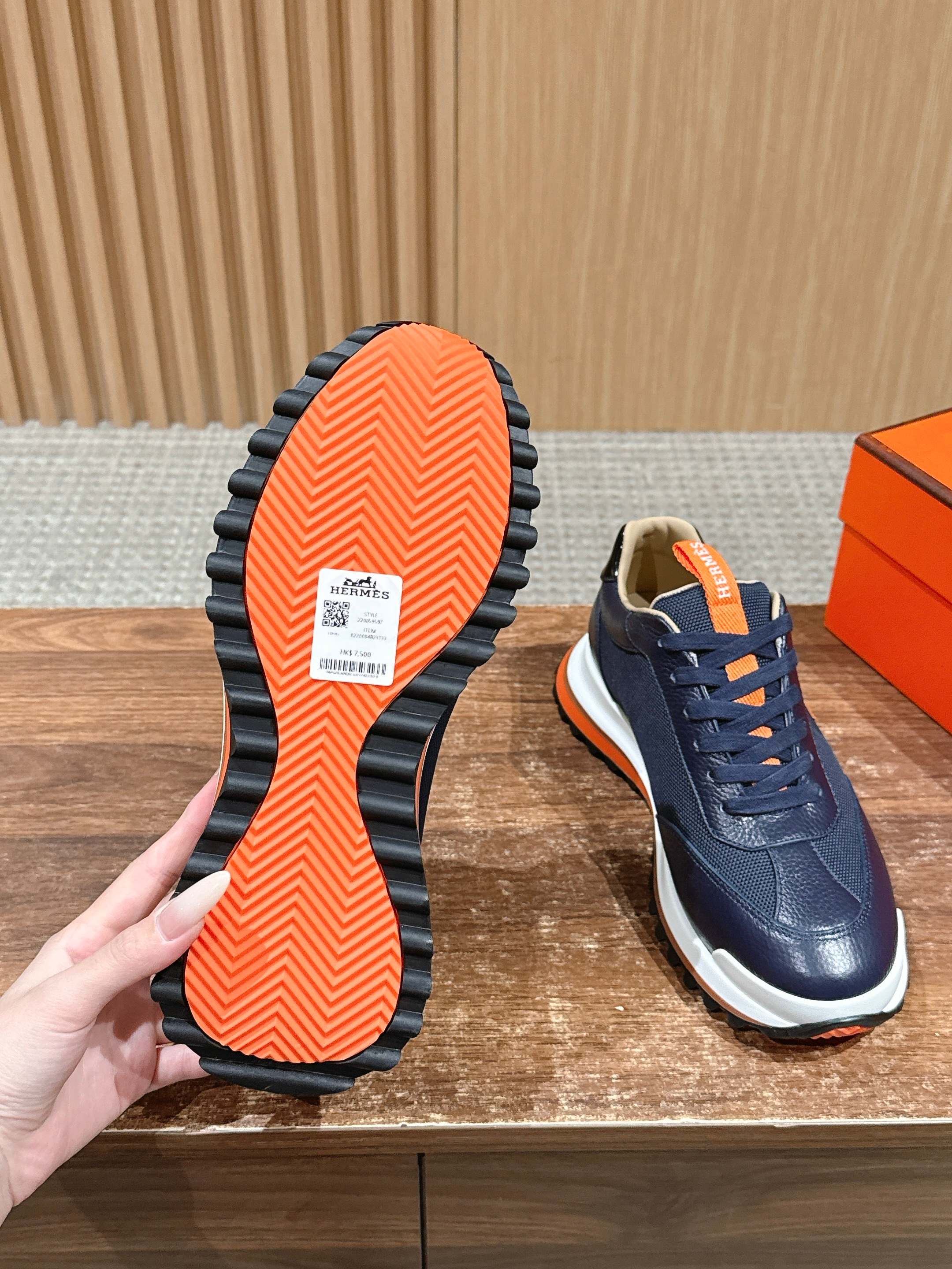 Hermes unisex navy sneakers with orange outsole, lace-up, white sole, bottom view