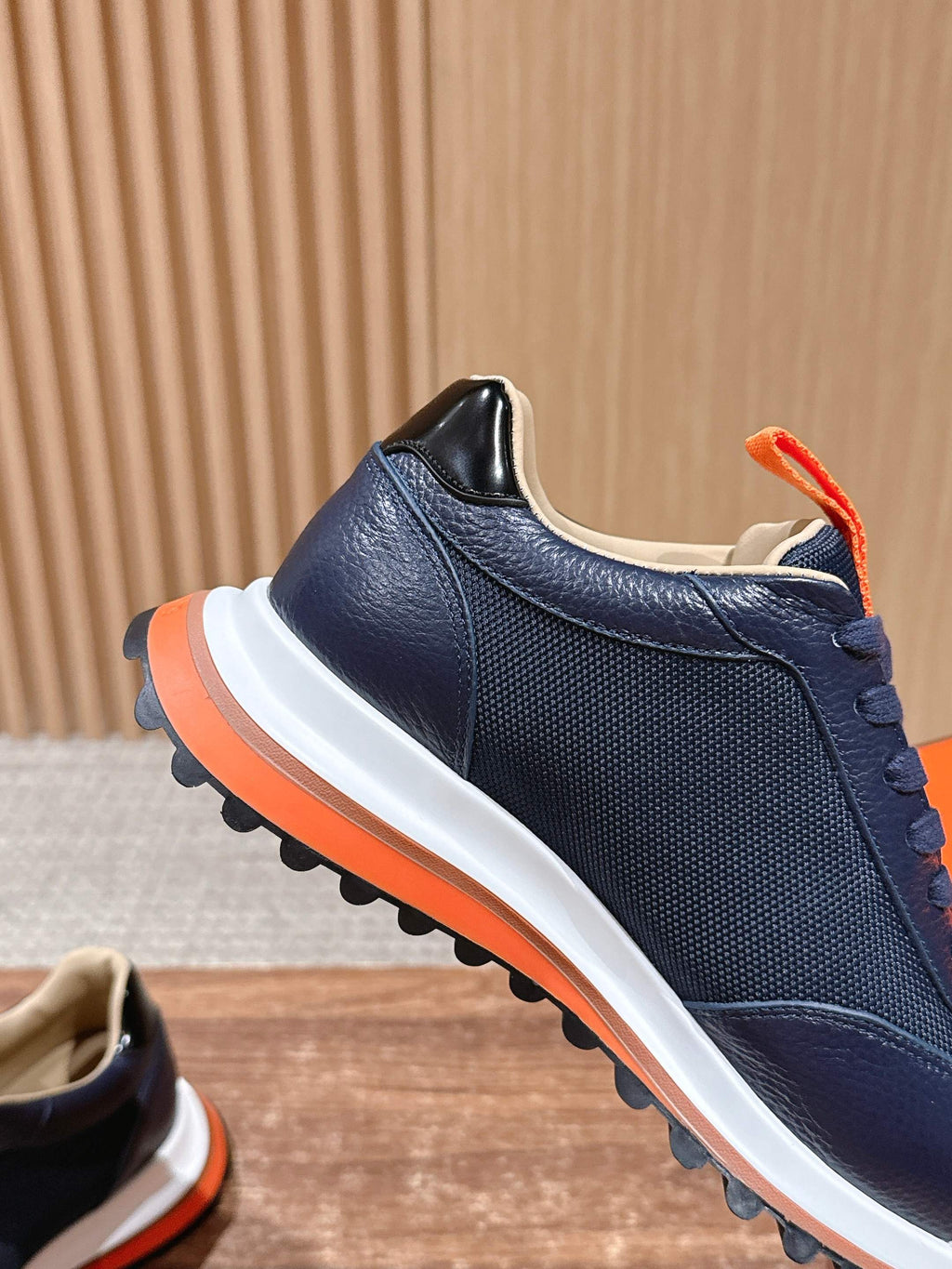 Hermes unisex navy sneakers with orange collar trim and white midsole, side view