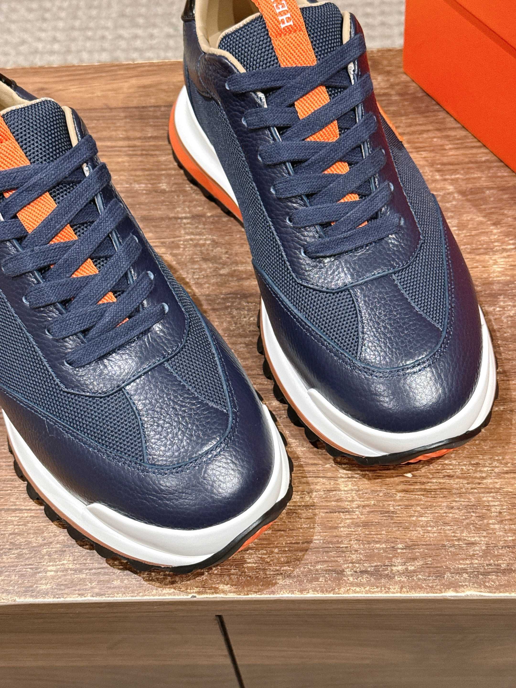 Hermes unisex navy lace-up sneakers with orange accents and white soles, pair view