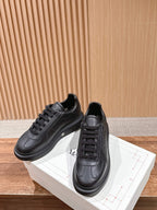 Black leather lace-up sneakers resting on a white box, side view