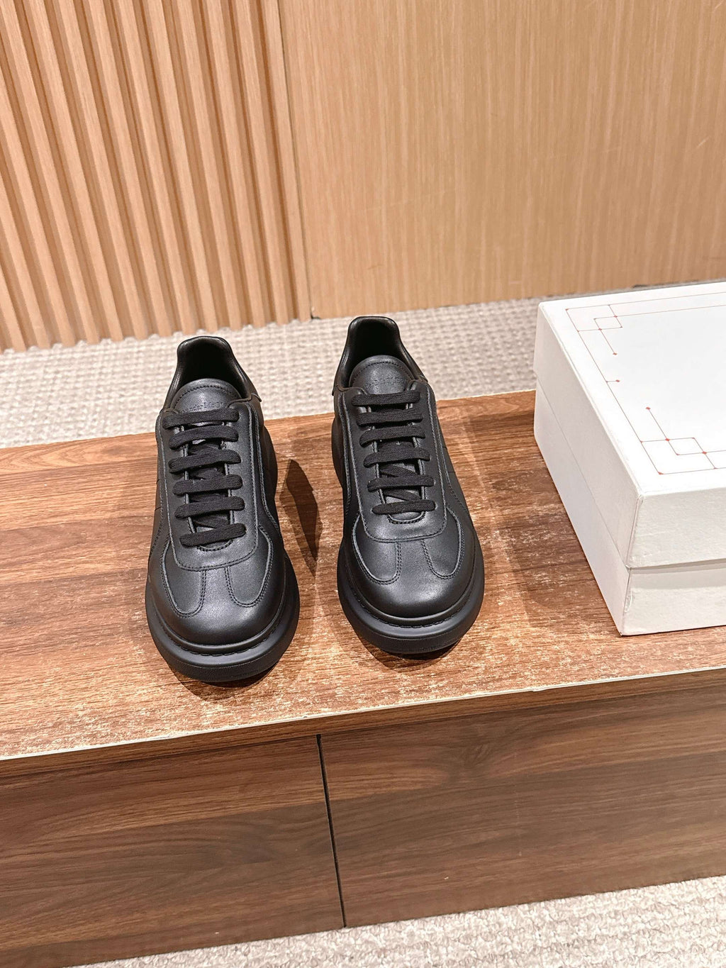 Pair of black leather lace-up sneakers with textured rubber sole and round toe