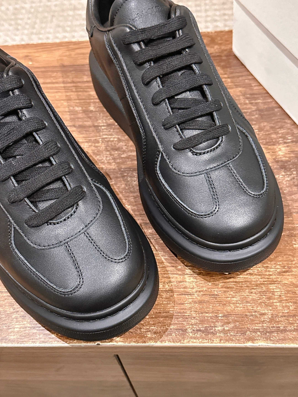 Close-up of black leather lace-up sneakers with stitched toe and eyelets