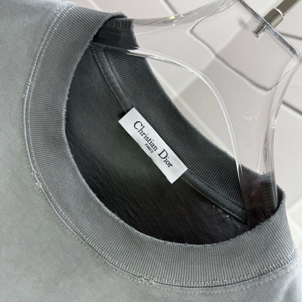 Light gray short-sleeve T-shirt crew neck with Christian Dior brand label tag.