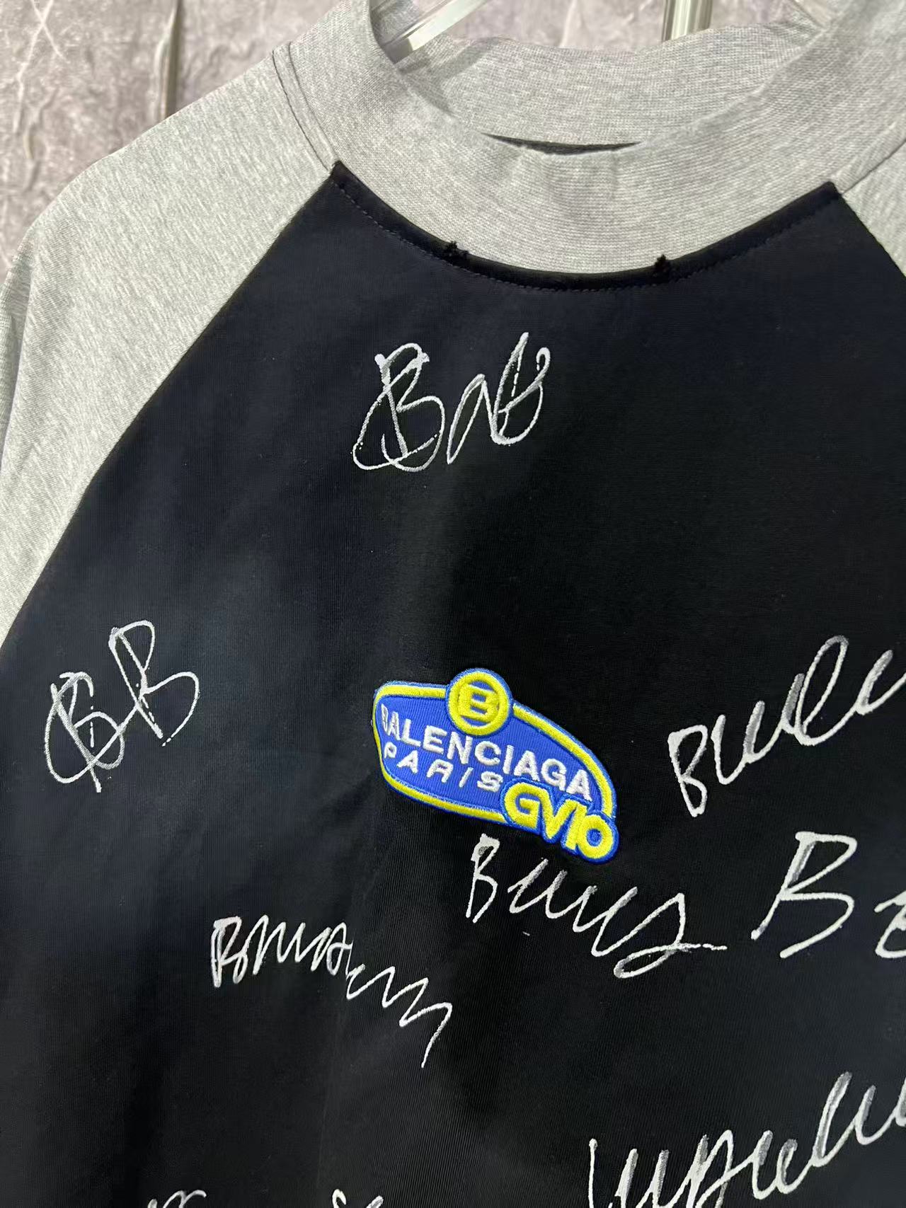 Black raglan T-shirt with logo patch graphic and cursive lettering
